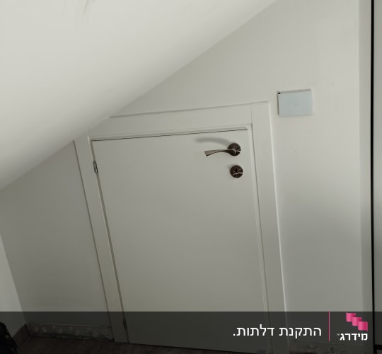 דלת קטנה עם ידית מתכת מתחת למדרגות